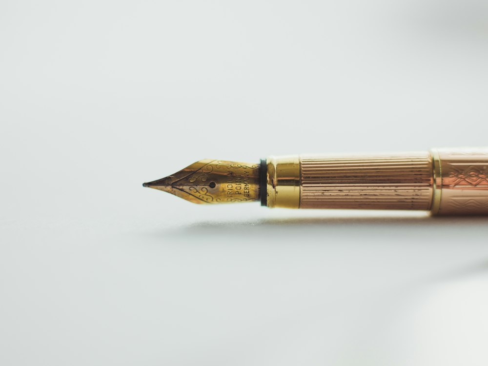 A gold fountain pen resting on white paper